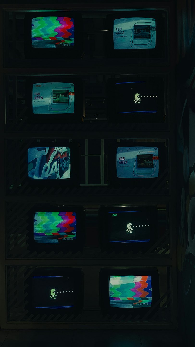 Twelve vintage televisions displaying different analog test patterns and graphics.