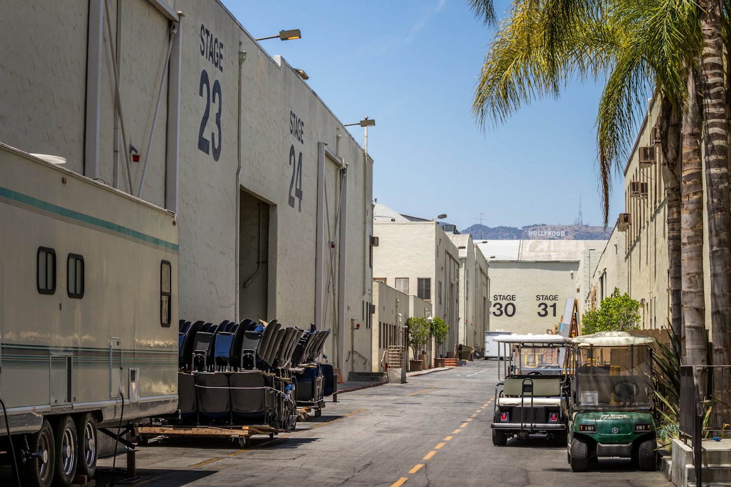 Sound stages on a studio backlot with the Hollywood sign in the distance.